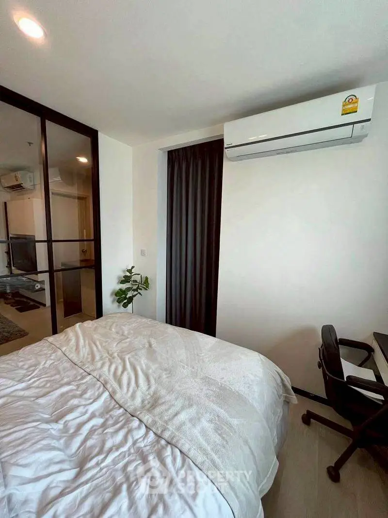 Modern bedroom with air conditioning and workspace, featuring a cozy bed and sleek design.