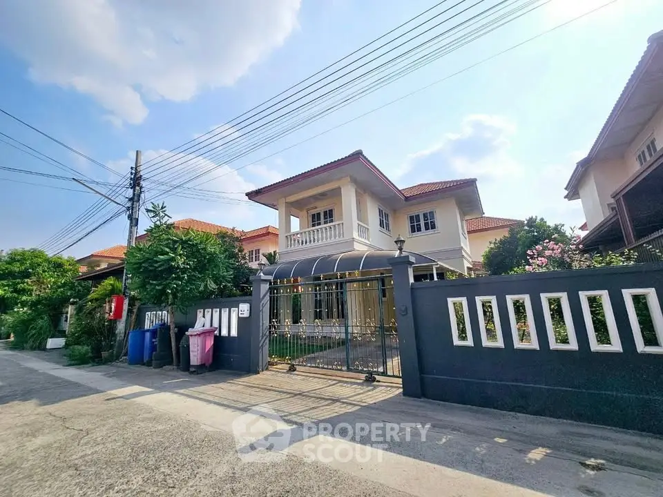 Charming two-story house with gated entrance and lush greenery in a serene neighborhood.