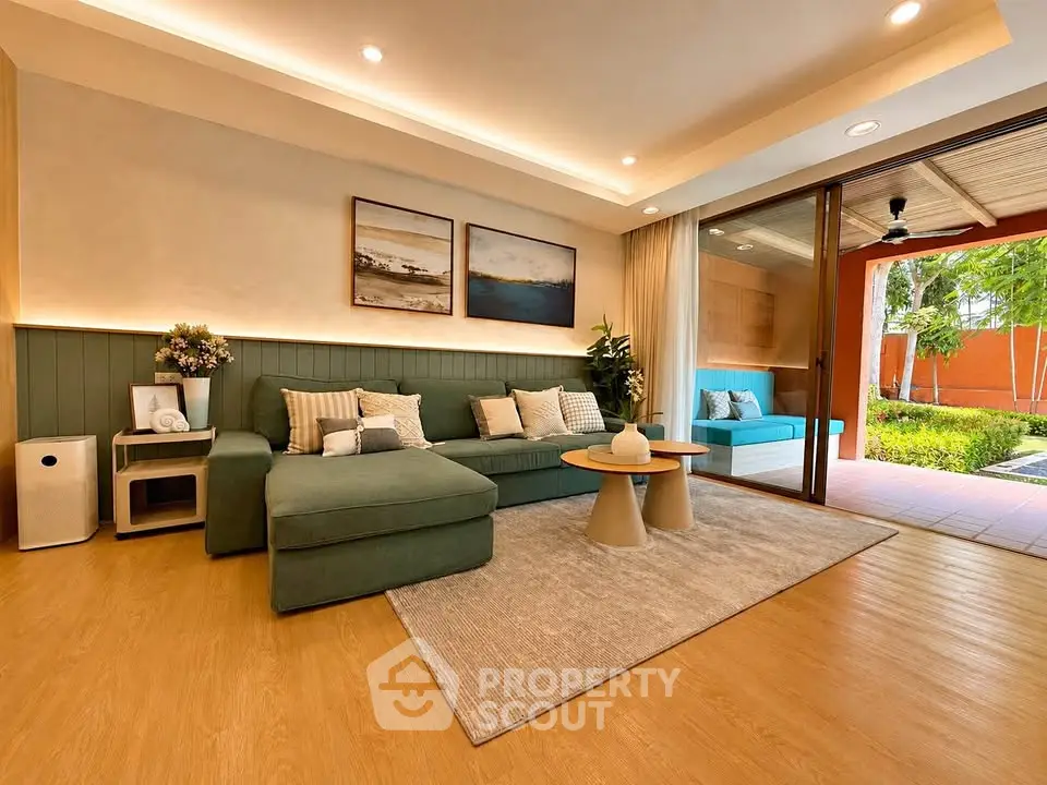 Spacious living room with modern decor and garden view, featuring a cozy seating area and elegant lighting.