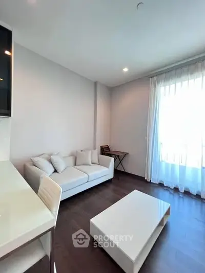 Modern living room with sleek white furniture and large window for natural light.
