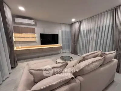 Modern living room with elegant sofa, wall-mounted TV, and stylish curtains.