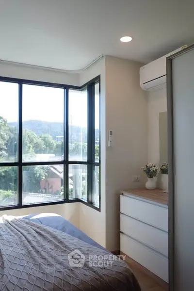 Bright bedroom with large windows offering scenic views and modern decor.