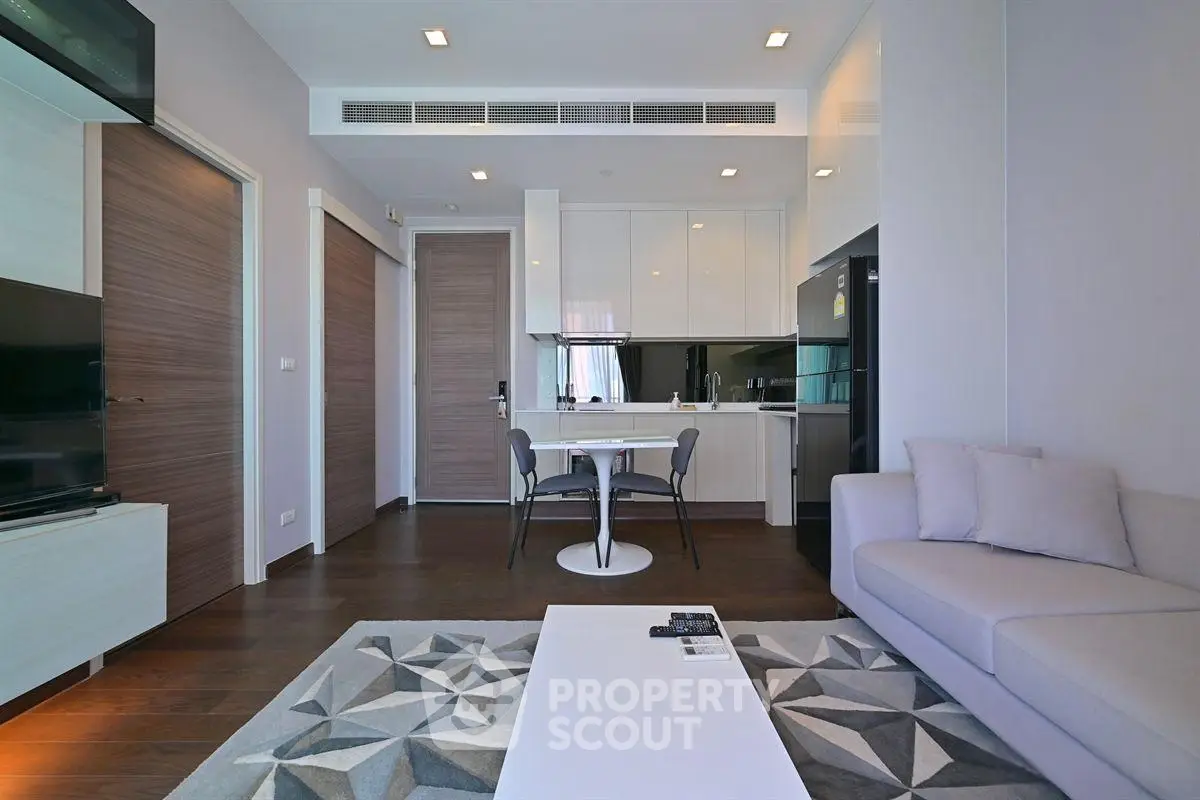 Modern living room with sleek kitchen, cozy sofa, and stylish decor in a contemporary apartment.