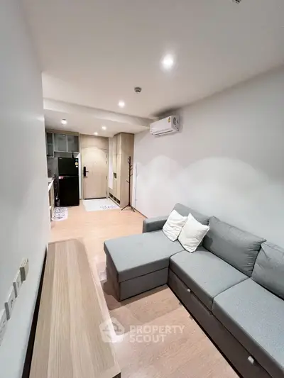 Modern living room with sleek furniture and open kitchen layout, perfect for urban living.