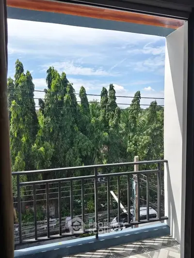 Charming balcony view with lush greenery and clear blue sky, perfect for relaxation.