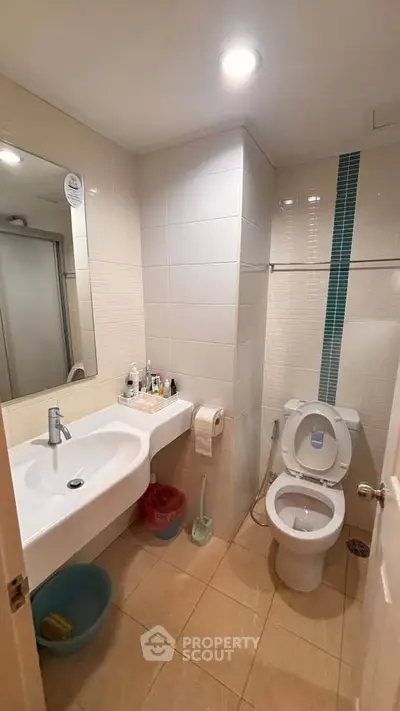 Modern bathroom with sleek sink and toilet, featuring stylish tile accents and ample lighting.