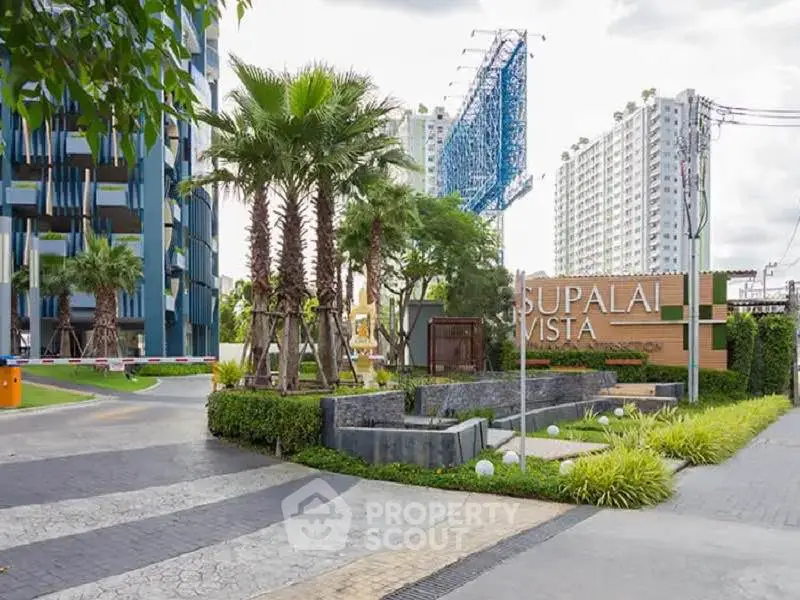 Modern condominium entrance with lush landscaping and contemporary design.