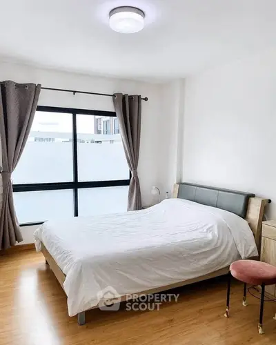 Bright and cozy bedroom with large window and modern furnishings