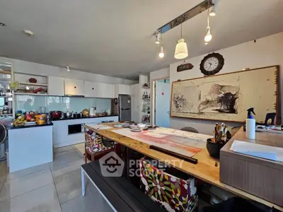 Spacious kitchen with modern appliances and artistic decor, featuring a large dining table and stylish lighting.