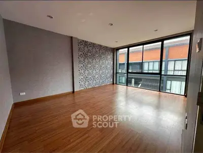 Spacious empty room with large windows and wooden flooring in modern building.