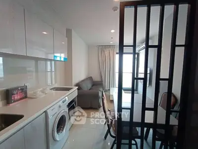Modern apartment interior with sleek kitchen and cozy living area, featuring a washing machine and stylish decor.