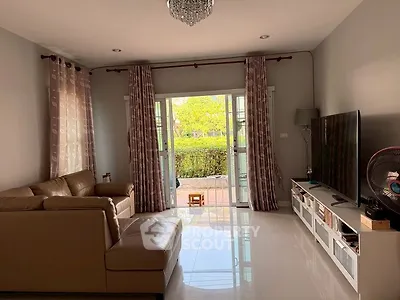 Spacious living room with large TV and garden view, perfect for relaxation.