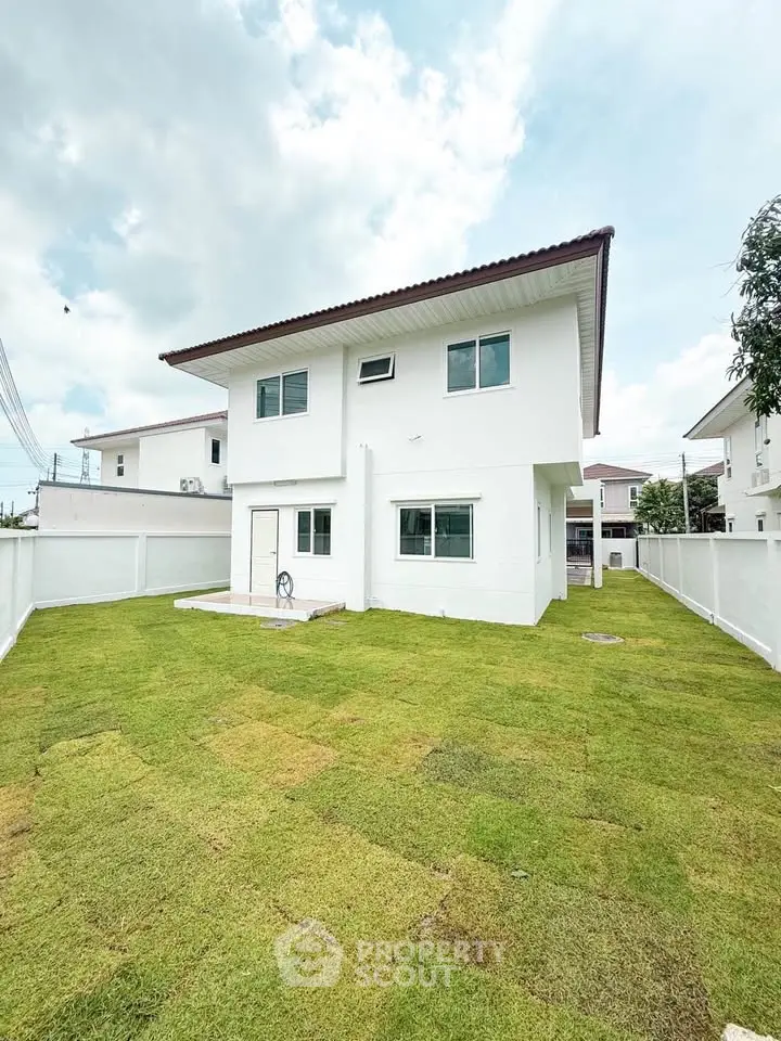 Spacious two-story white house with lush green lawn and modern design, perfect for family living.
