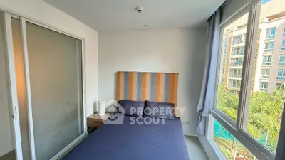 Cozy bedroom with large windows offering a pool view in a modern apartment.