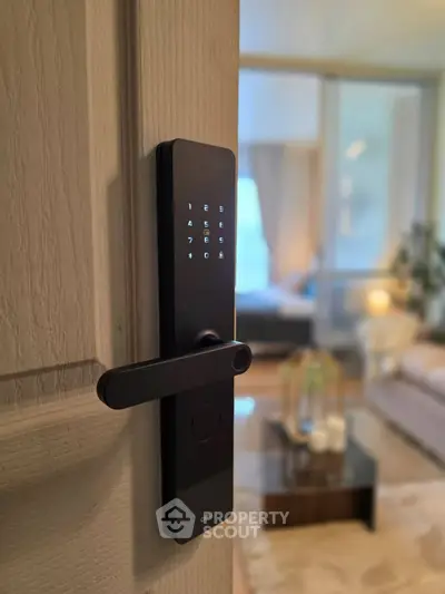 Modern smart lock on door with cozy living room in background