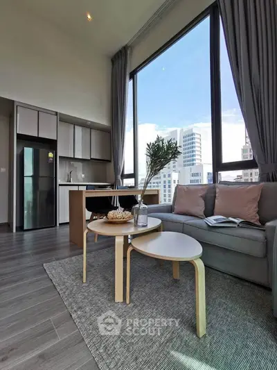 Modern living room with large windows and city view, featuring stylish furniture and open kitchen layout.