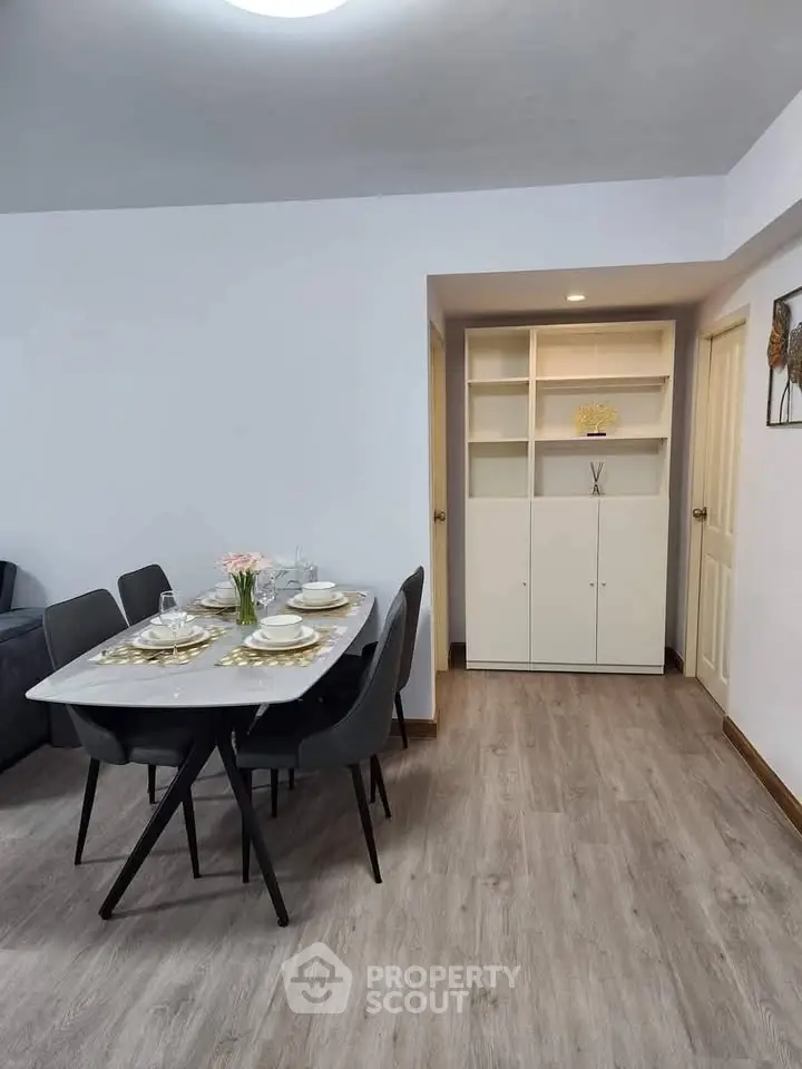 Modern dining area with elegant table setting and built-in shelving in a cozy apartment.