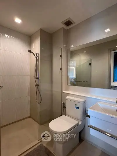 Modern bathroom with glass shower and sleek fixtures in contemporary apartment.