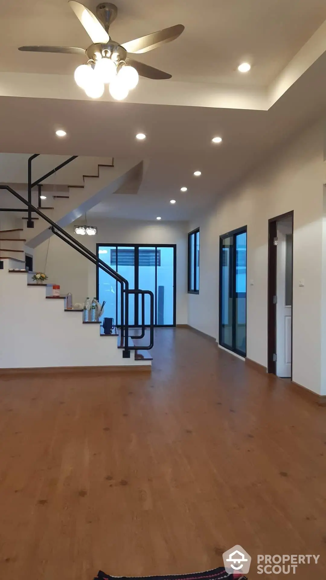 Spacious living area with polished wooden floors, modern lighting, and an elegant spiral staircase leading to the upper level, perfect for family gatherings and entertaining guests.