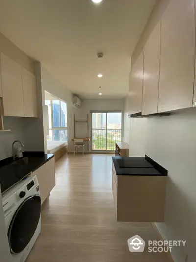 Modern kitchen with sleek cabinets and washing machine, offering a bright and airy space with city views.