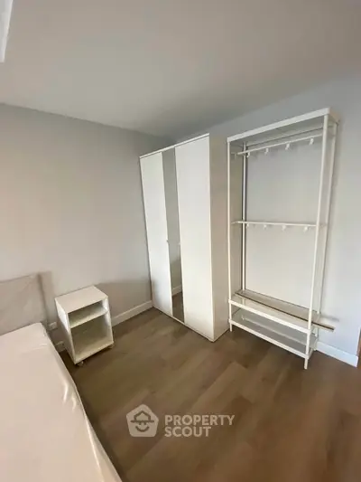 Spacious bedroom with modern wardrobe and wooden flooring in a minimalist design.