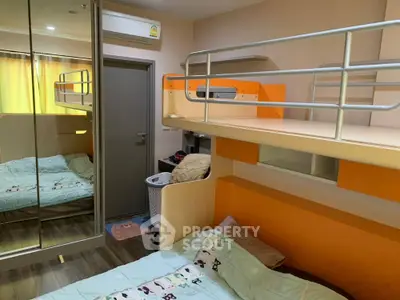 Compact and modern bedroom with bright orange bunk beds, mirrored wardrobe, and wood flooring, ideal for maximizing small living spaces.