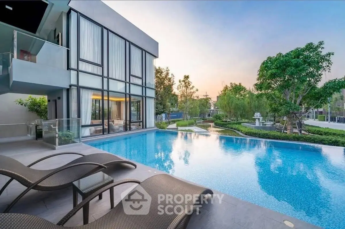 Luxurious modern home with stunning pool and garden view at sunset.