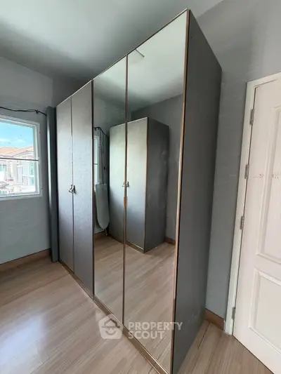 Spacious bedroom with sleek mirrored wardrobe and wooden flooring