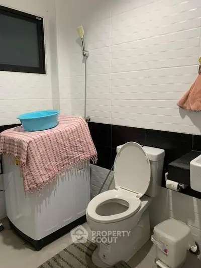 Modern bathroom with washing machine and shower in a compact space.