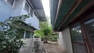 Charming exterior view of a unique architectural property with lush greenery and spacious pathways.