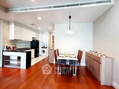 Modern open-layout kitchen and dining area with sleek design and wooden flooring.