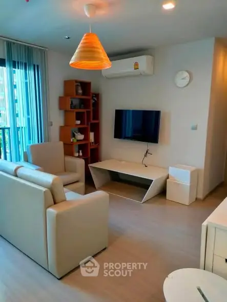 Modern living room with sleek furniture and wall-mounted TV in a cozy apartment.