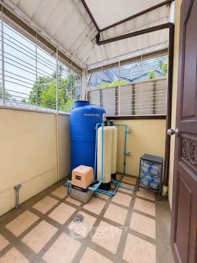 Outdoor water filtration system on tiled balcony with roof and metal railings.