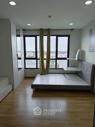 Modern bedroom with large windows and wooden flooring, offering a bright and airy atmosphere.