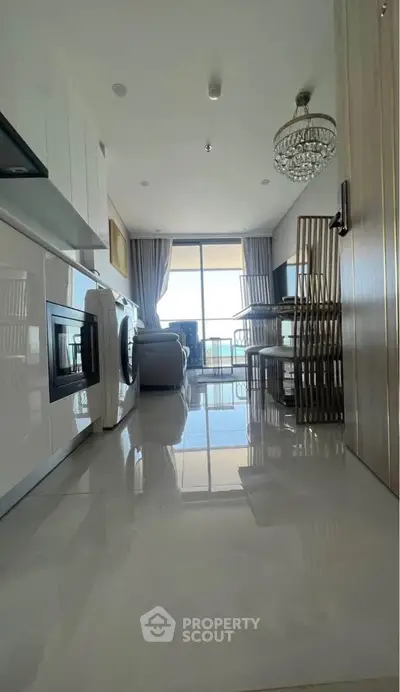 Modern kitchen with open layout and balcony view, featuring sleek appliances and elegant dining area.
