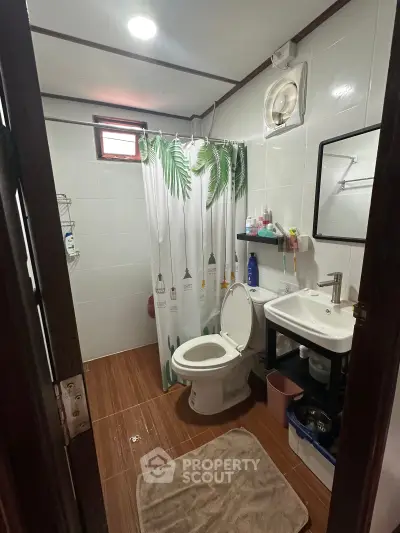 Cozy bathroom with modern fixtures and tropical-themed shower curtain, perfect for relaxation.