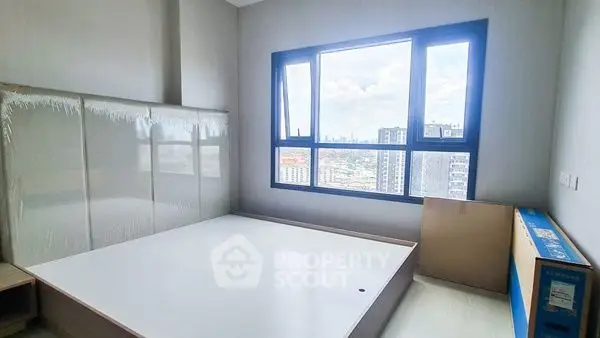 Spacious bedroom with large window offering stunning city views in modern apartment.