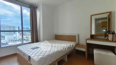 Modern bedroom with large window offering stunning city views, featuring a comfortable bed and stylish vanity.