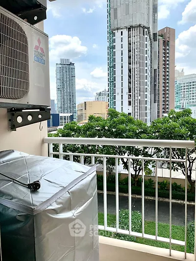 City view from a balcony with air conditioning unit, showcasing urban skyline and greenery.