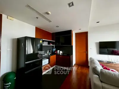 Modern kitchen with sleek black appliances and cozy living area in open layout apartment.