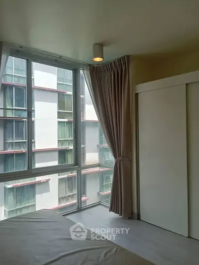 Bright bedroom with large windows and modern curtains in a high-rise building.
