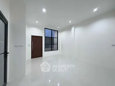 Spacious modern living room with high ceilings and large window, perfect for natural light.