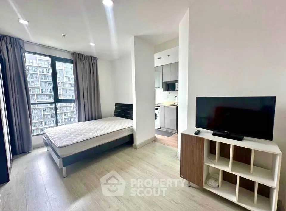 Modern studio apartment with large window and open kitchen layout