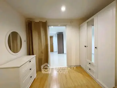 Spacious bedroom with elegant white furniture and wooden flooring, perfect for modern living.