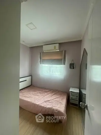 Cozy bedroom with pink bedding and air conditioning in a modern apartment.