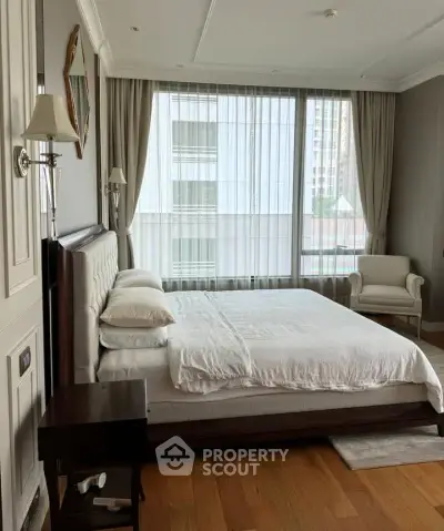 Spacious bedroom with large windows and elegant decor in modern apartment.