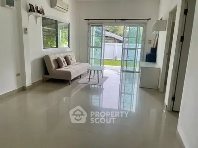 Spacious living room with large windows and garden view, featuring modern sofa and sleek flooring.