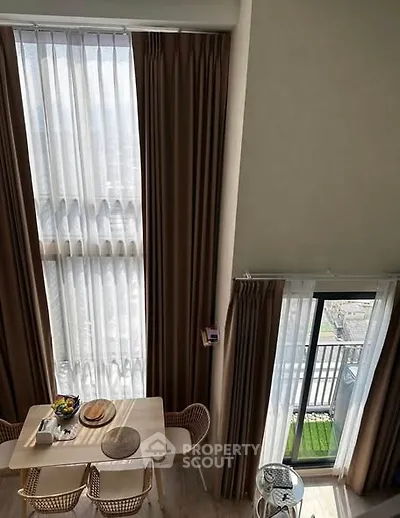 Elegant dining area with tall windows and balcony view, perfect for modern living.