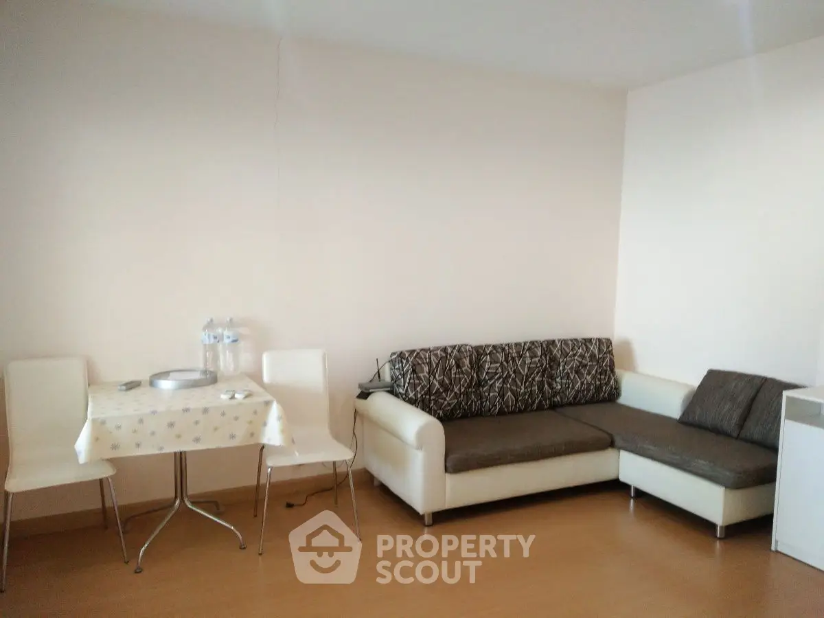 Cozy living room with modern sofa and dining area, perfect for small gatherings.