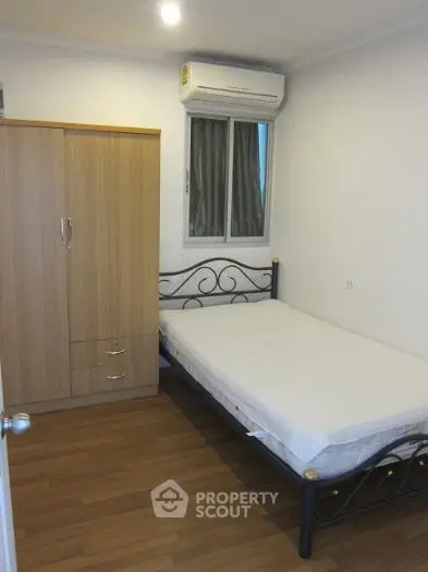 Cozy bedroom with wooden wardrobe and metal bed frame, featuring air conditioning.